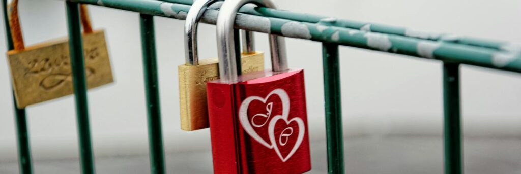 A vibrant red love padlock with heart engravings on a bridge railing symbolizing eternal love.