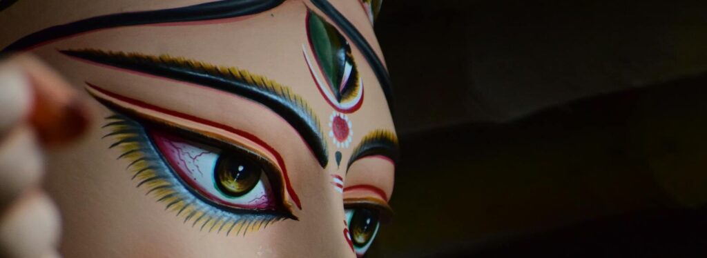 A detailed close-up of a colorful Durga statue's face from Kolkata, showcasing intricate makeup.