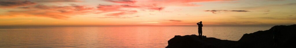 person top of mountain near body of water