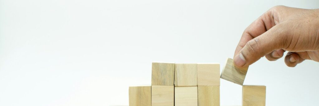 A person placing a block into a pile of wooden blocks