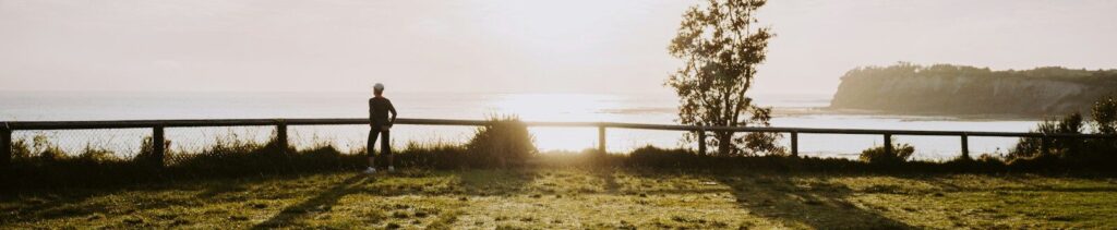 a person standing on a grass covered hill overlooking a body of water