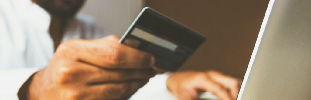 person using laptop computer holding card