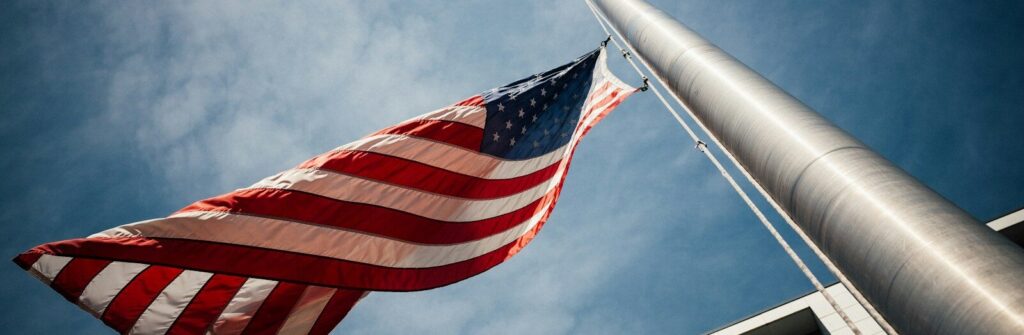 low-angle photo of U.S. flag placed on gray pole