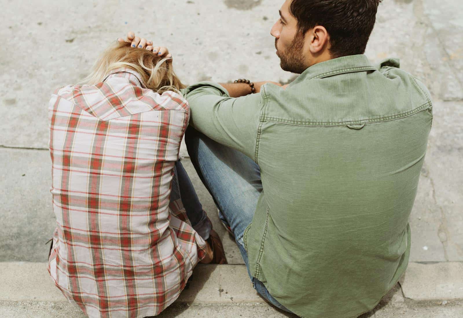 A couple sitting on the street, engaged in a distressed conversation, capturing a moment of emotional tension. Zodiac Sign relationship.