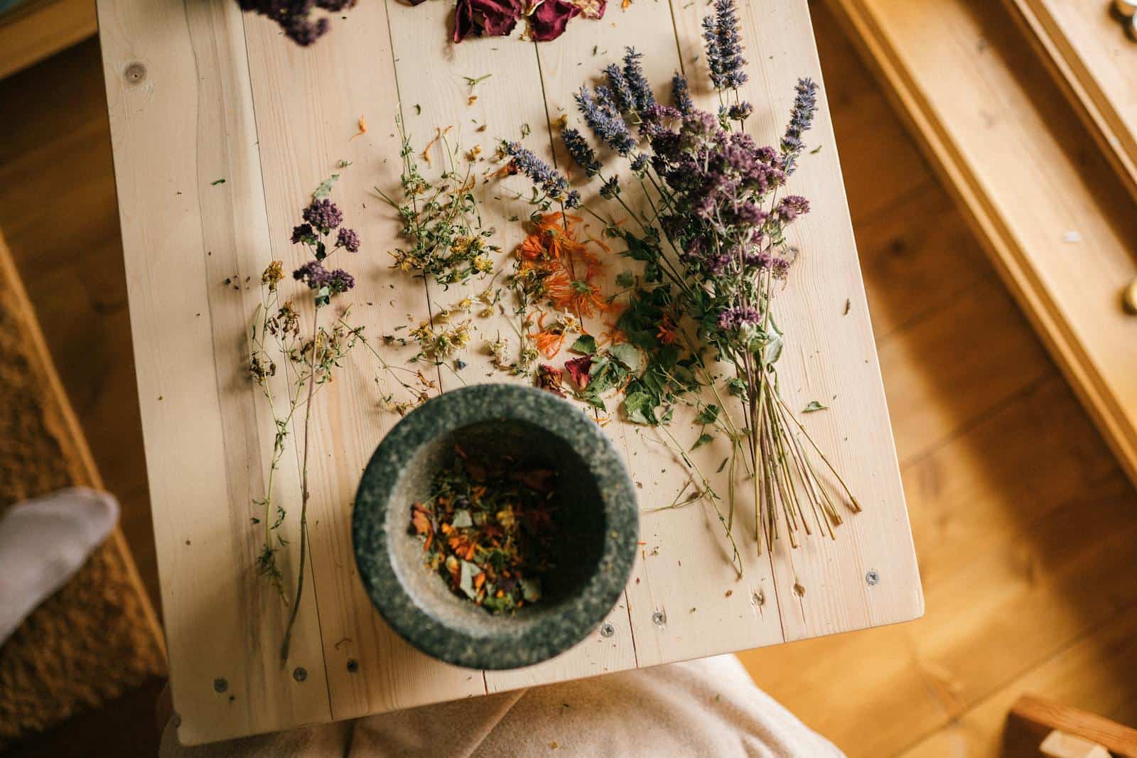 Dried herbs and flowers arranged on a wooden table with a stone mortar for home remedies. Traditional Medicine