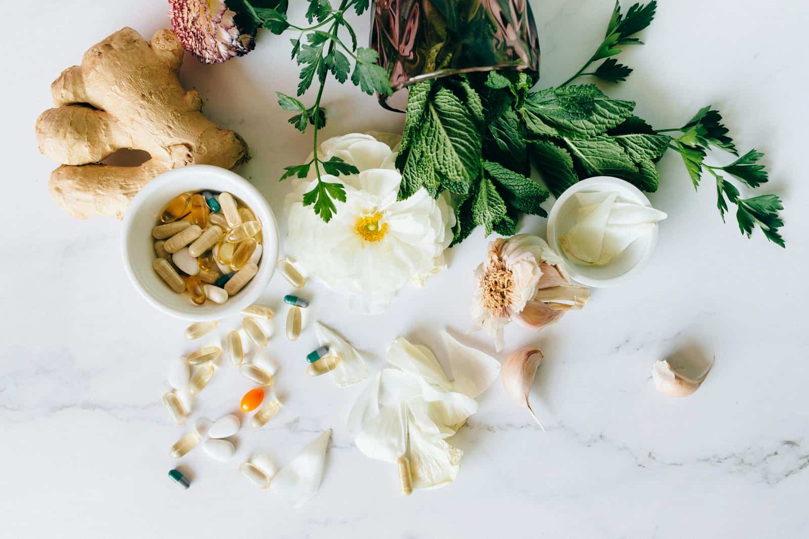 A flatlay of herbal supplements with fresh ginger, garlic, and leaves. traditional medicine