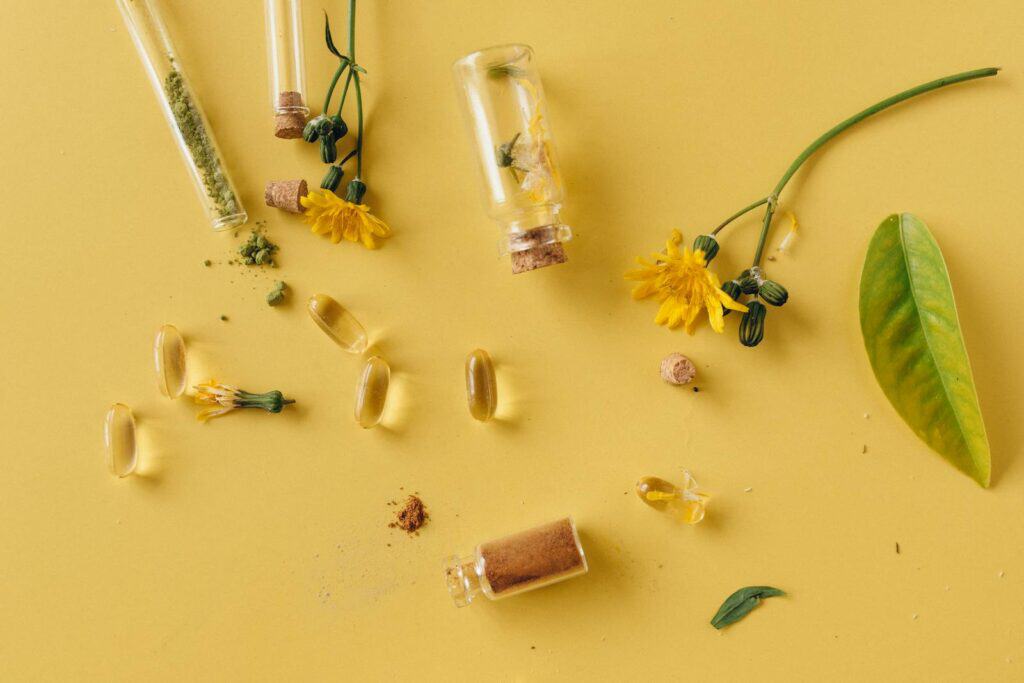 Natural Supplements, A flat lay of glass bottles, capsules, and flowers on a vibrant yellow surface, representing natural remedies.