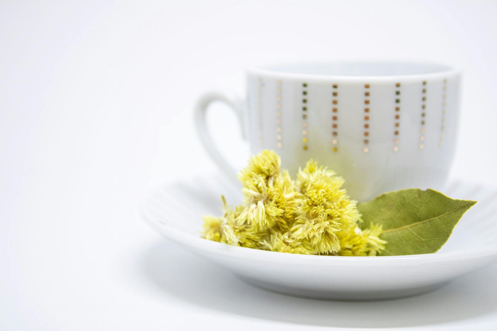 Natural medicine, A minimalist teacup with yellow flowers and a leaf, perfect for zen and relaxation themes.
