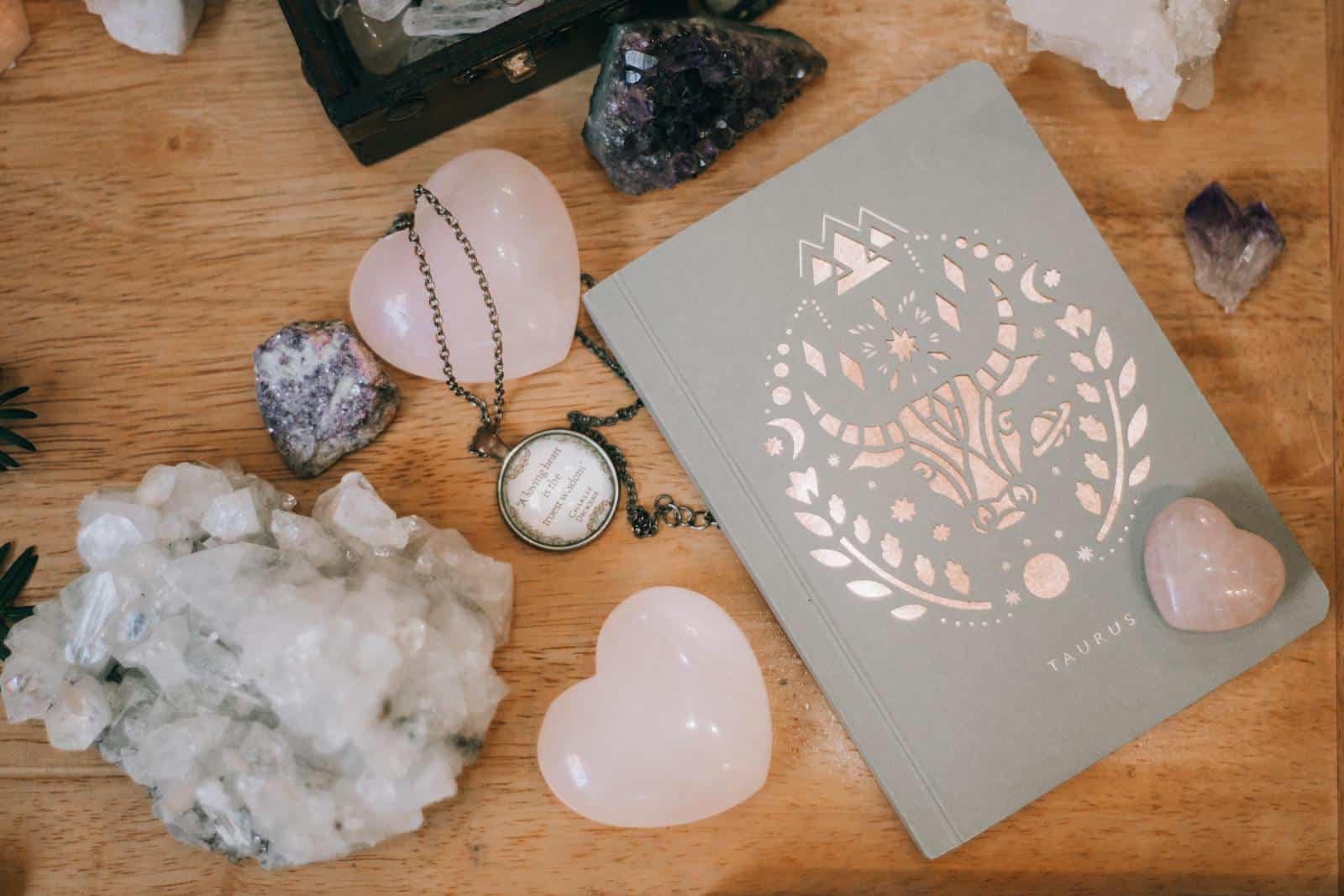 Astrology, Zodiac, Horoscope, Taurus-themed notebook surrounded by heart-shaped and raw crystals on a wooden surface, evoking tranquility.