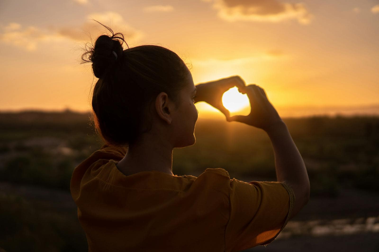 A silhouette of a young woman forming a heart shape at sunset in Kelâat M'Gouna, Morocco.
planetary movements, health, wellness, mindfulness, birth chart, zodiac, self-care