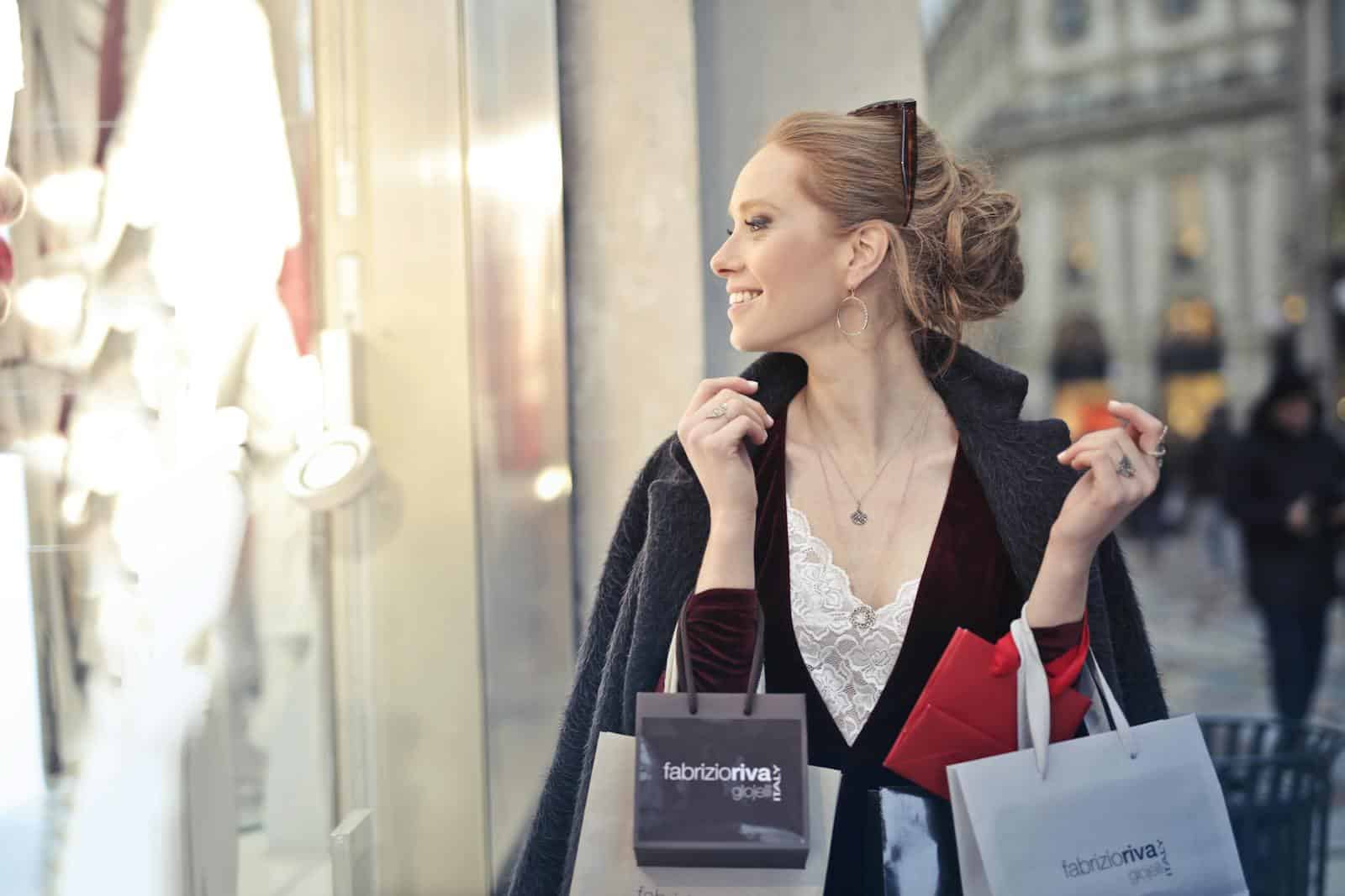 Smiling woman holding shopping bags in a city, enjoying a day of shopping. finances, zodiac, astrology, spending habits