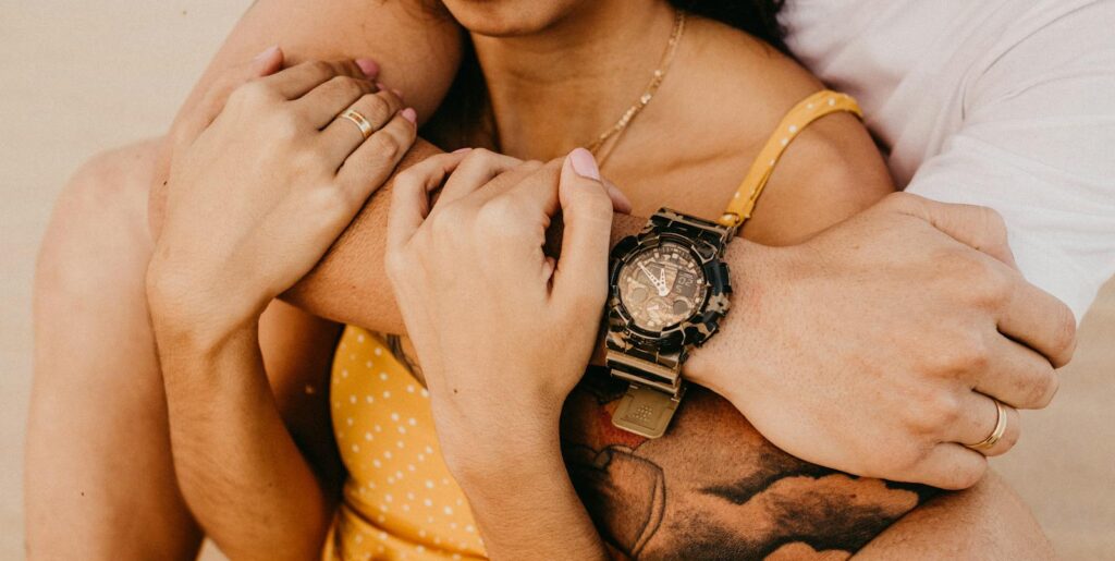 Warm, intimate close-up of a couple embracing, highlighting a stylish wristwatch. Trusted Psychic, Spiritual Guidance, Life Advice