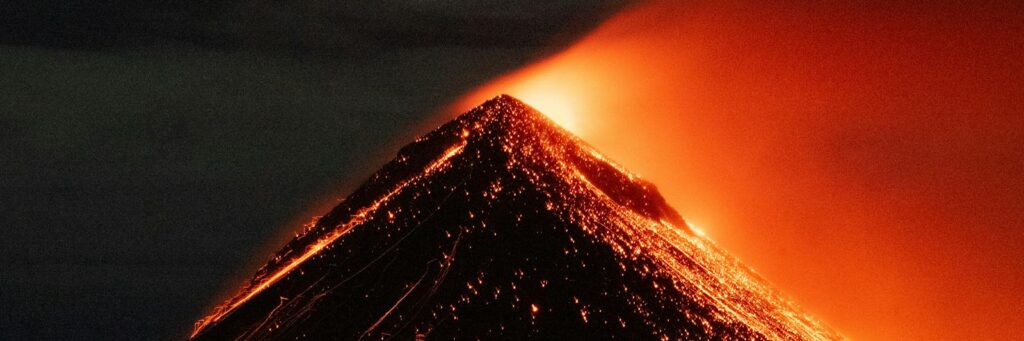 Captivating nighttime eruption of Acatenango volcano in Guatemala, showcasing flowing lava and ash.