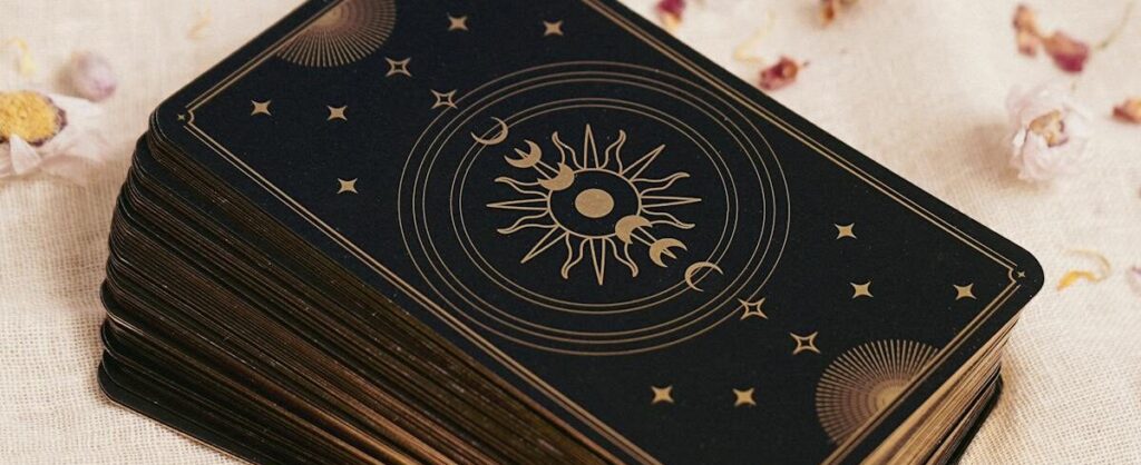 A stacked deck of tarot cards with celestial design on a beige fabric background. Archetype, astrology, midhaven