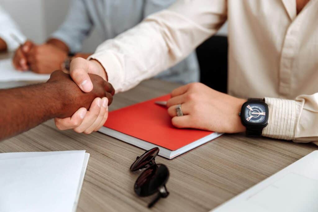Close-up of a handshake over a desk with documents, signifying partnership. astrology, zodiaccompatibility, compositechart, relationshipastrology, karmicrelationships