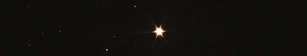 A single bright star shining in a dark, clear night sky with scattered distant stars.